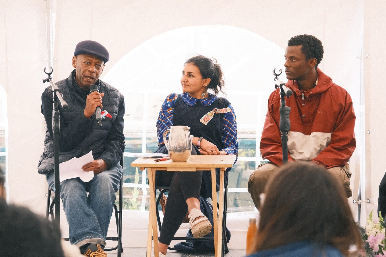 Three panellists speaking to a seated audience in a marquee at a Nourishing Economics retreat