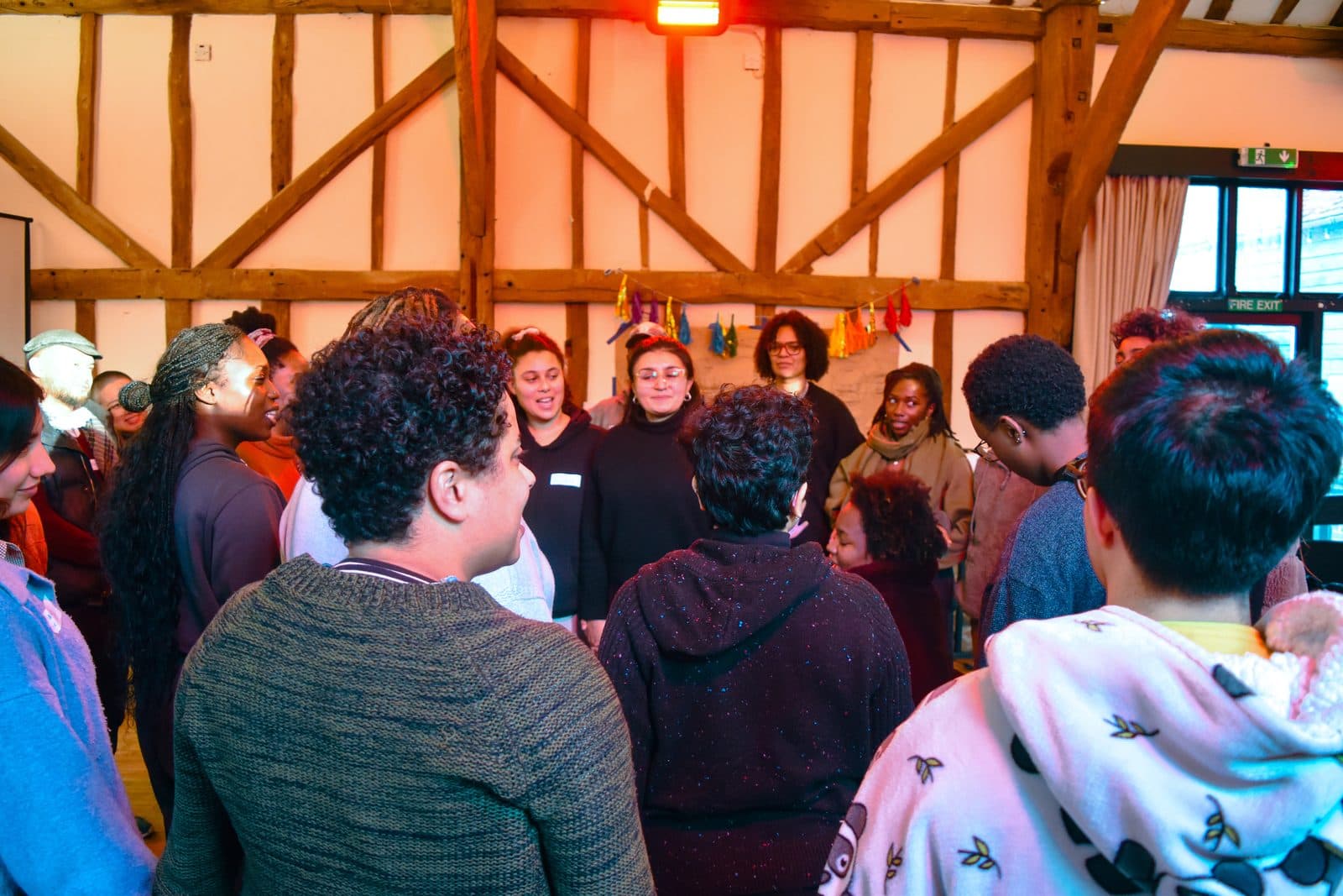 Group of participants gathered in a circle inside a timber-framed barn during a Nourishing Economics retreat