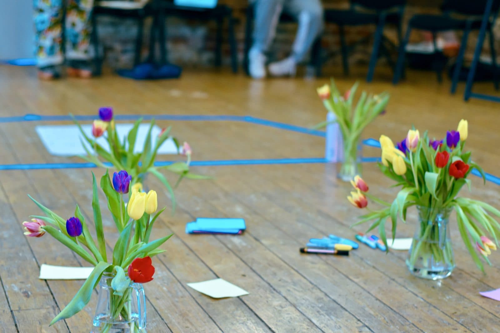 Vases of colourful tulips on a wooden floor during a Nourishing Economics retreat session